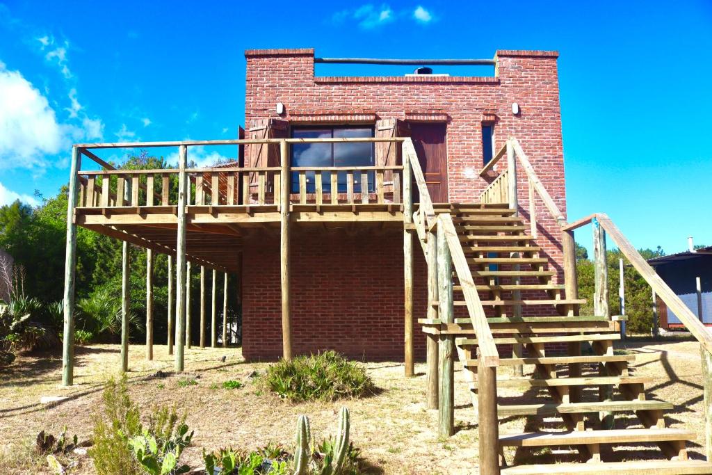 een bakstenen gebouw met een houten trap erop bij Castillito de la viuda casa para 5o 6 personas in Punta Del Diablo