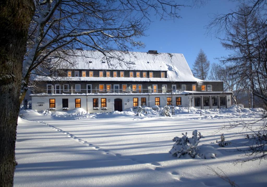 un gran edificio blanco con nieve en el suelo en Berghotel Hoher Knochen - Ruhe & Natur, en Winterberg