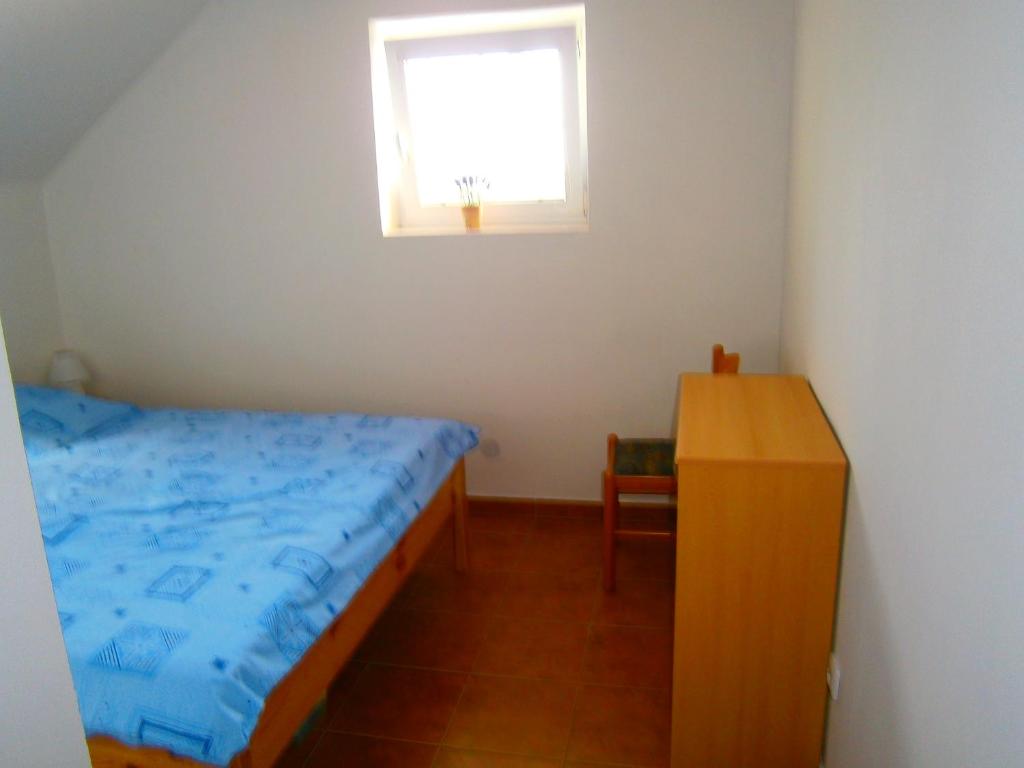 a small bedroom with a bed and a window at Penzion Andrea in Velké Bílovice