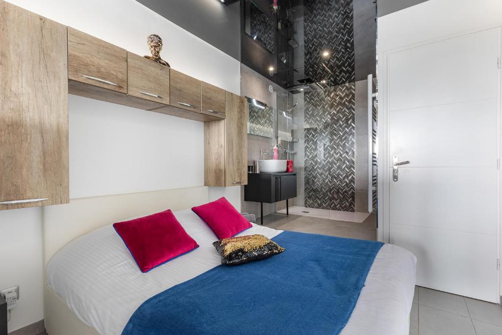 a bedroom with a large bed with red and blue pillows at Village Naturiste R4N - Le Bocca Port Nature Coursive Luxe in Cap d'Agde