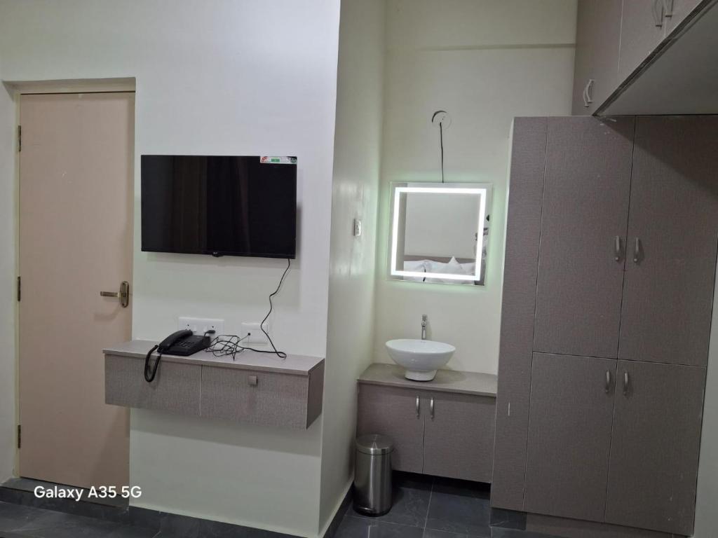 een badkamer met een wastafel en een televisie aan de muur bij AG Corporate Stay in Mahindra World City in Singapperumālkovil