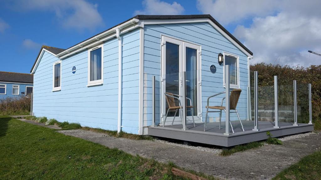 a blue tiny house with two chairs on the porch at C25 Weir View, Riviere Towans in Hayle