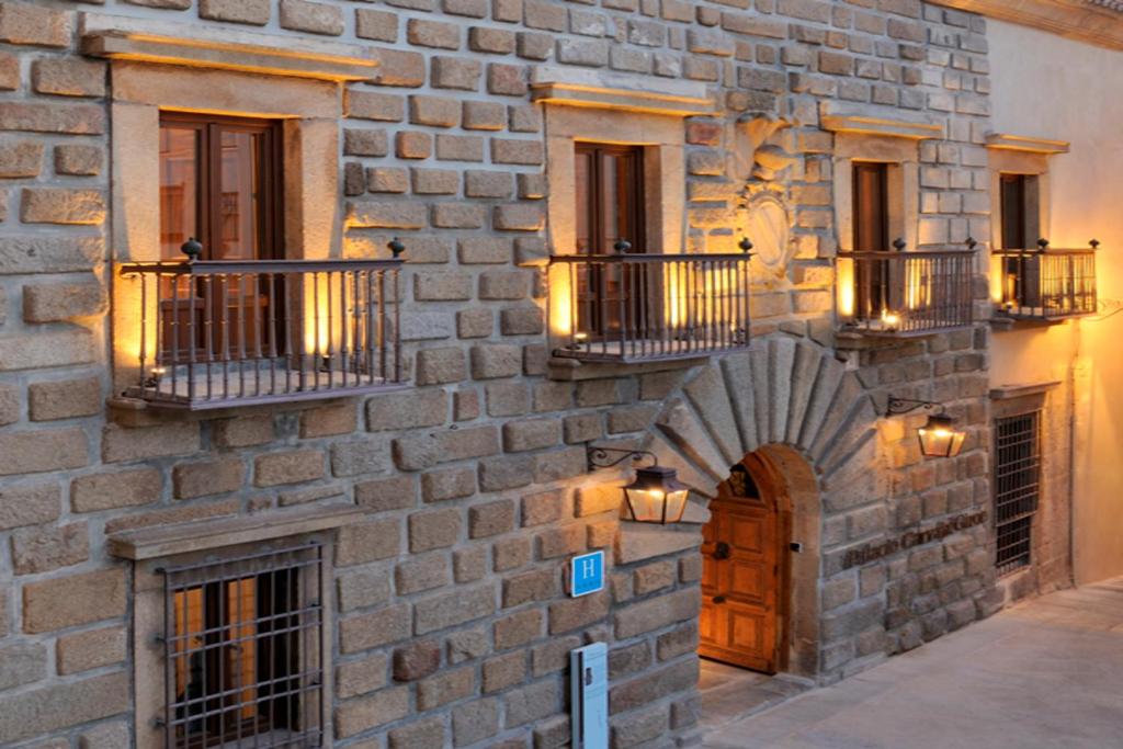 un bâtiment en briques avec une porte et des balcons. dans l'établissement Palacio Carvajal Girón, à Plasence