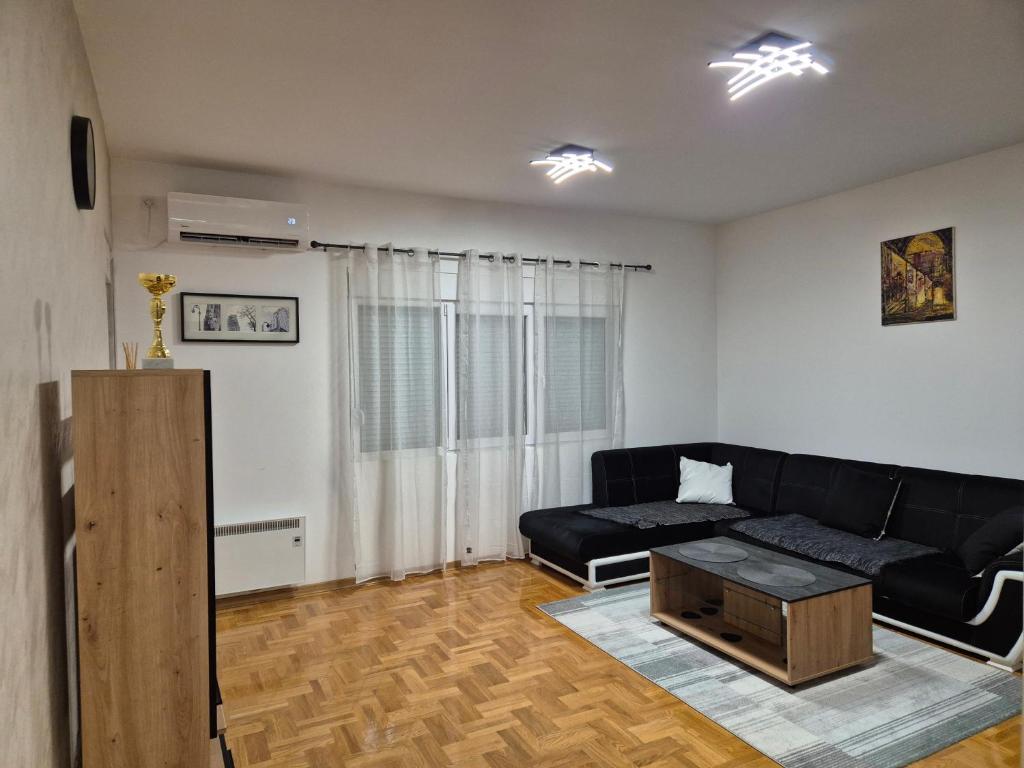 ein Wohnzimmer mit schwarzem Sofa und Couchtisch in der Unterkunft Teja- new apartment for 4 person with free parking space in Belgrad