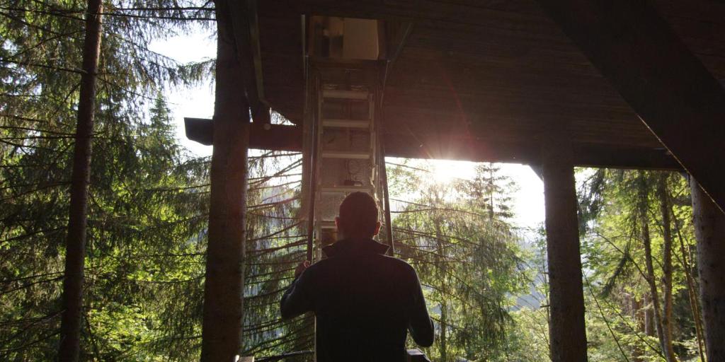 a man standing in front of a cross in a forest at Cabane entre terre et ciel in Saint-Nicolas-la-Chapelle