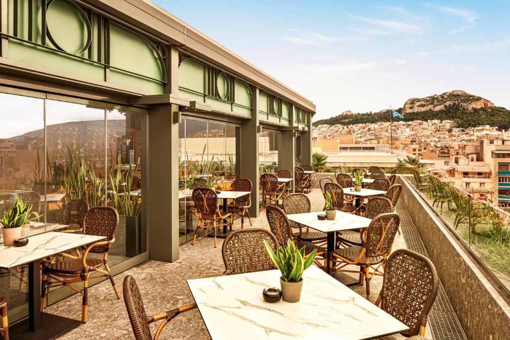 ein Restaurant mit Tischen und Stühlen auf einem Balkon in der Unterkunft Zeus Essence Athens Central, former Athens Key in Athen