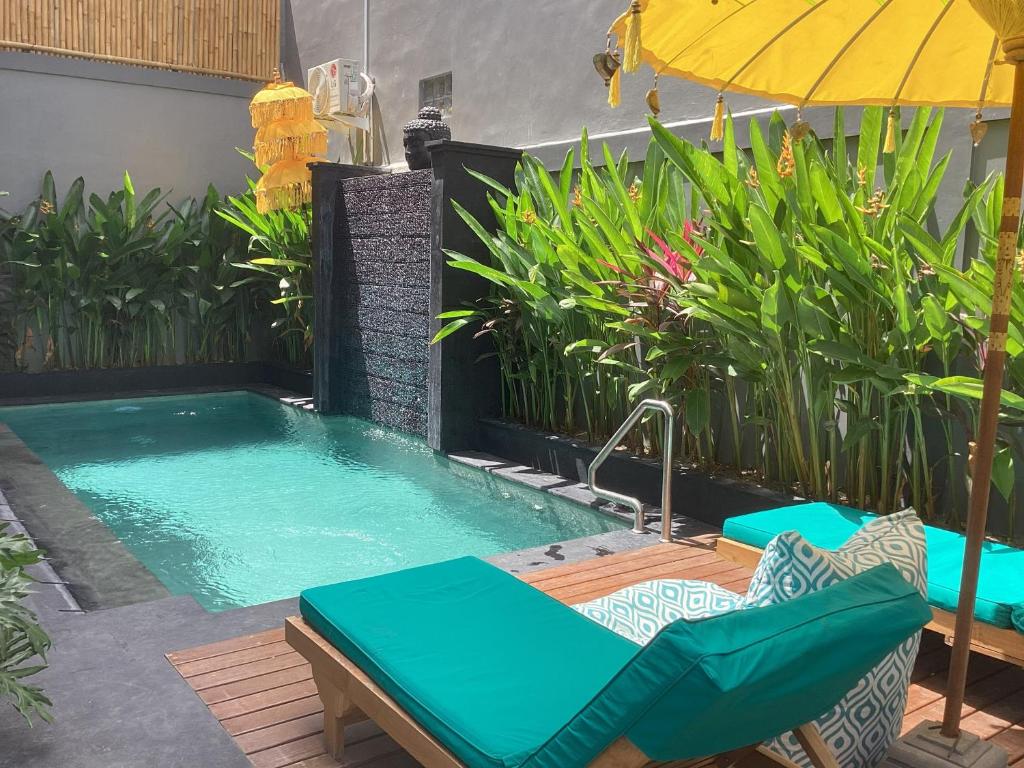 a small swimming pool with an umbrella and chairs at Villa Solas Legian in Legian