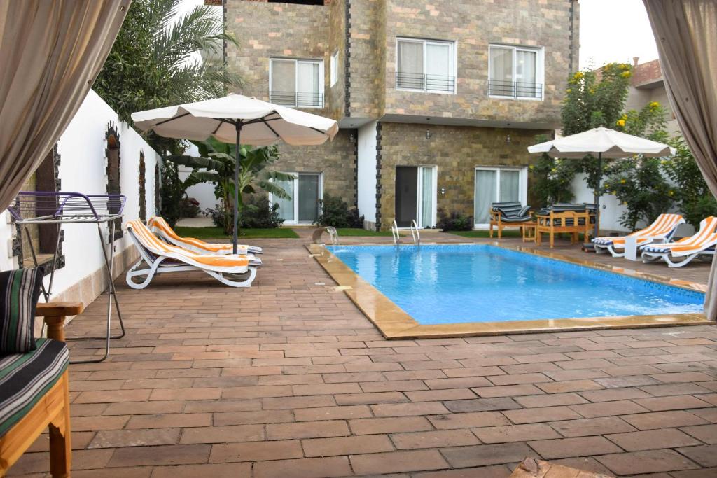 a swimming pool with chairs and umbrellas next to a building at Quiet Corner Apartment in Luxor