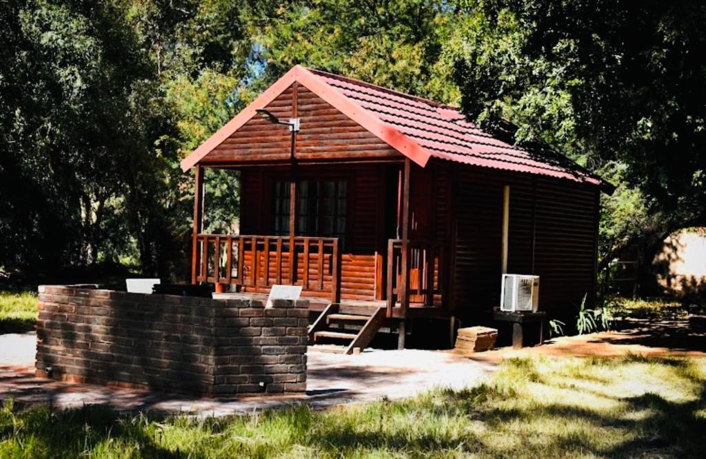 eine kleine Holzhütte mit einer Veranda in einem Park in der Unterkunft Lake Cabin in Olifantshoek