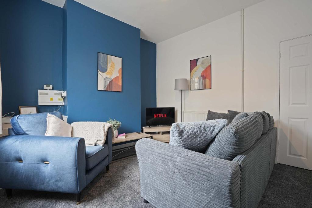 sala de estar con 2 sillas y pared azul en Cosy Home in Grimsby Town Centre, en Grimsby