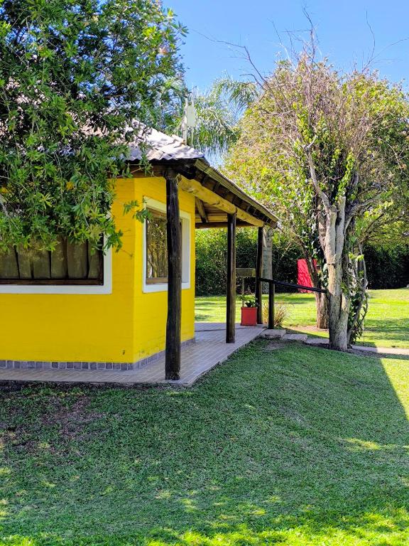 a yellow house with a deck in a yard at Cabañas La Soñada in Chajarí