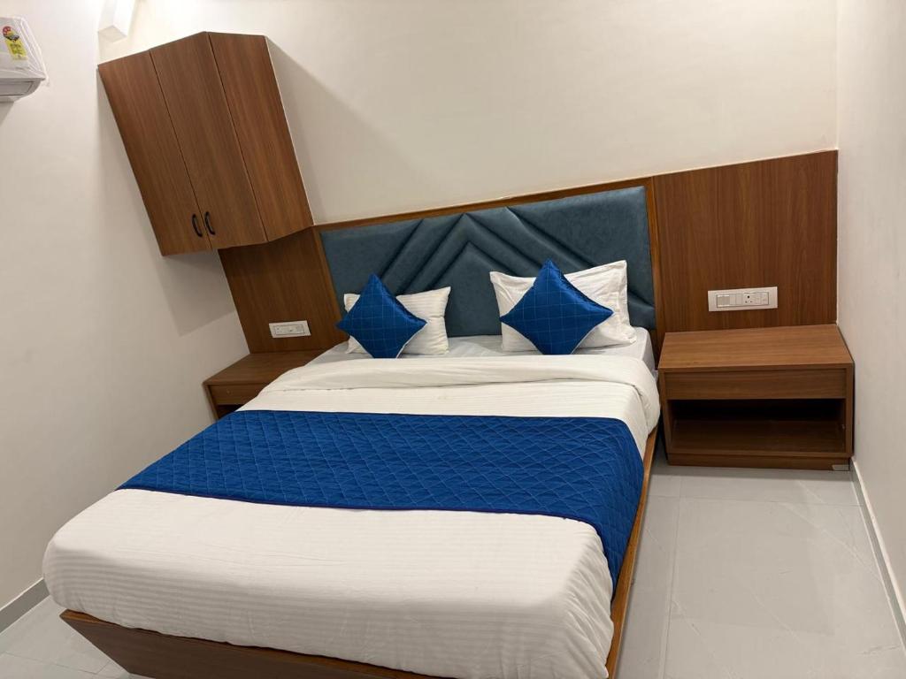 een slaapkamer met een blauw en wit bed met blauwe kussens bij Hotel Beral in Ahmedabad