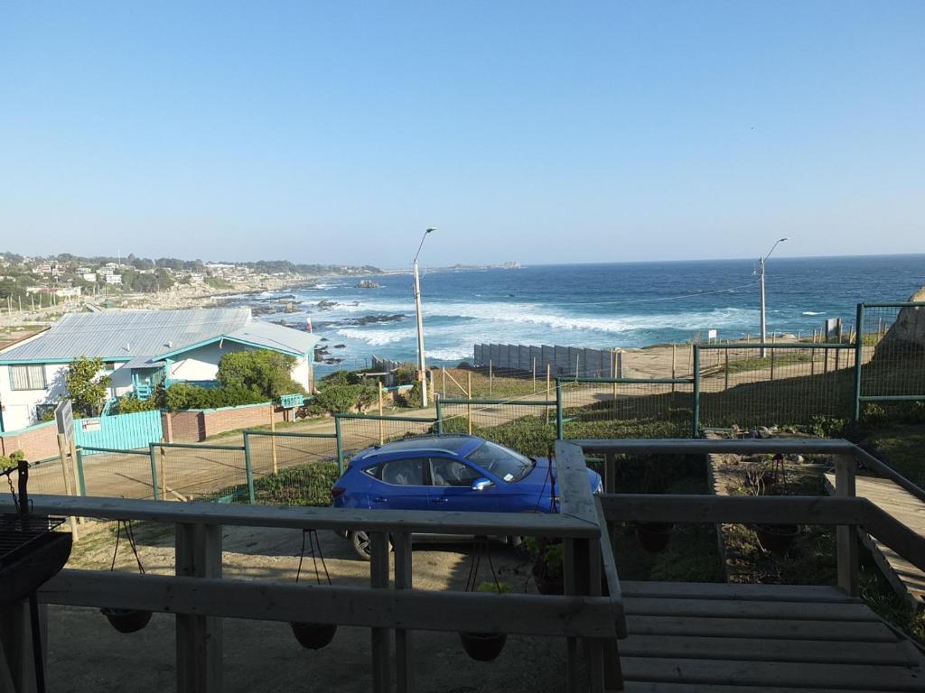 Un coche azul aparcado junto a la playa en Cabañas Vista Hermosa, en El Quisco