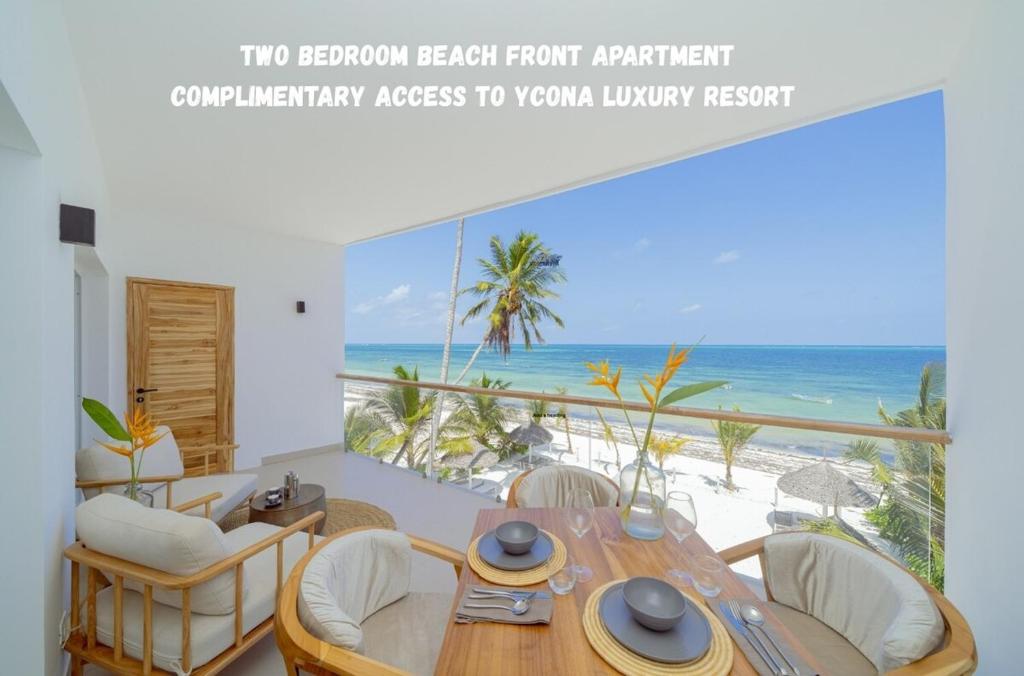 een eetkamer met een tafel en stoelen en de oceaan bij Two Bedroom Beach Front Apartment with pool in Kiwengwa