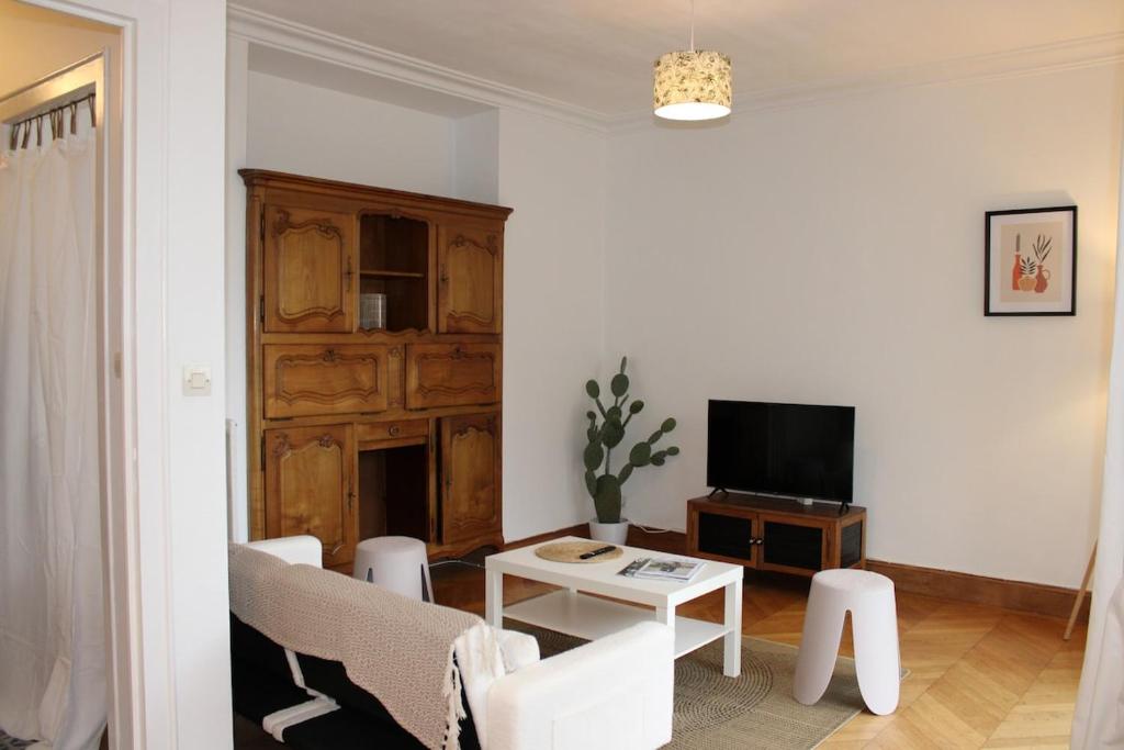 a living room with a tv and a table at Le TNB Rennes in Rennes