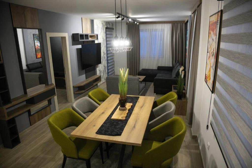 - un salon avec une table à manger et des chaises vertes dans l'établissement Apartmens in Kopaonik, à Kopaonik