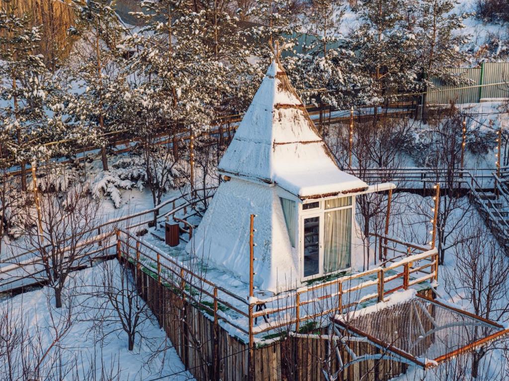 een gebouw met een met sneeuw bedekt dak in de sneeuw bij Pik Talgar Eco Village in Talghar
