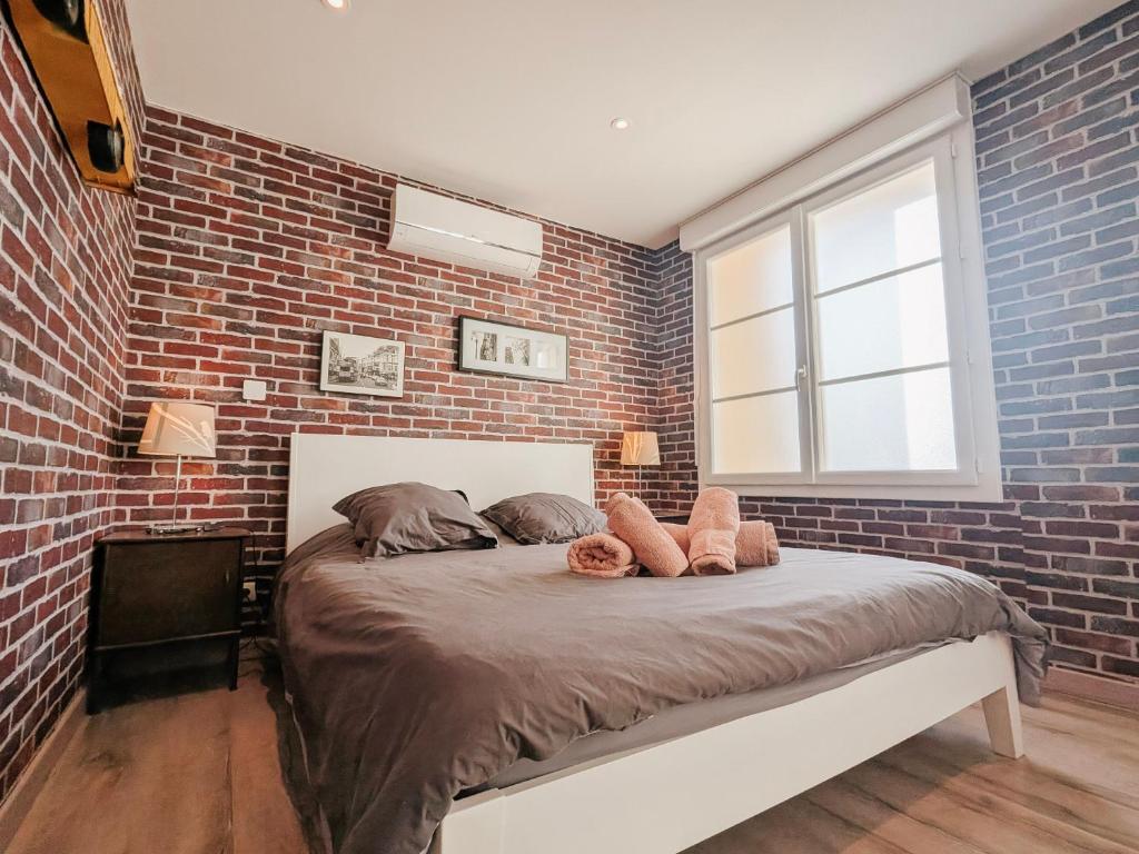 een slaapkamer met een bakstenen muur en een bed bij La Ressource, Claire in Fontguenand