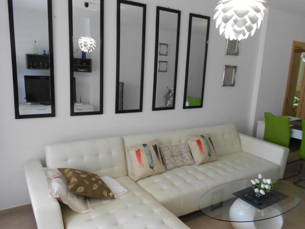 sala de estar con sofá blanco y algunos espejos en Playa Sol II Apartment, en Denia
