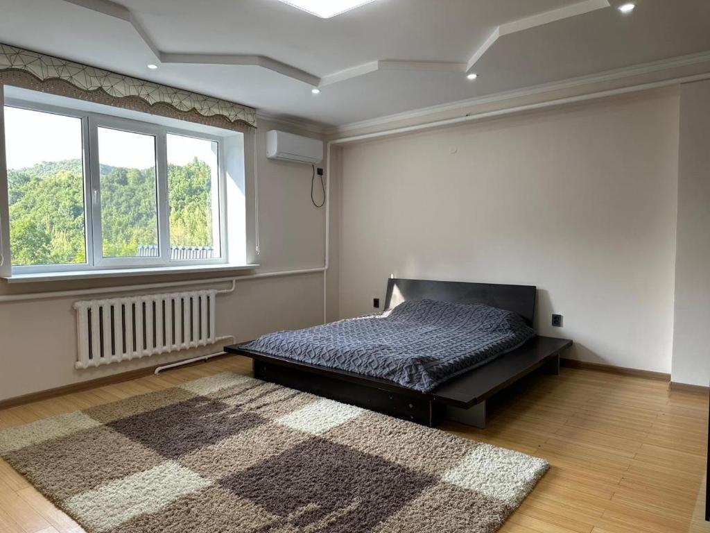 ein Schlafzimmer mit einem Bett und einem großen Fenster in der Unterkunft Villa Mountain Medeu in Almaty
