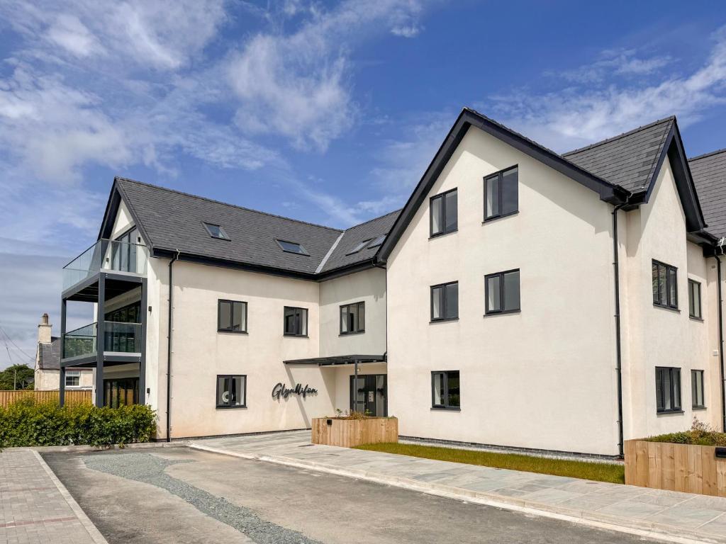 a white house with a black roof at Glynllifon 4 in Llanallgo