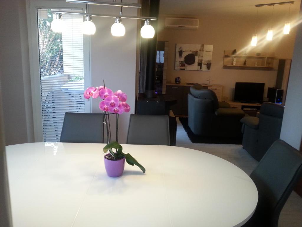 a white table with a vase with pink flowers on it at Apartments Roncevic in Zadar