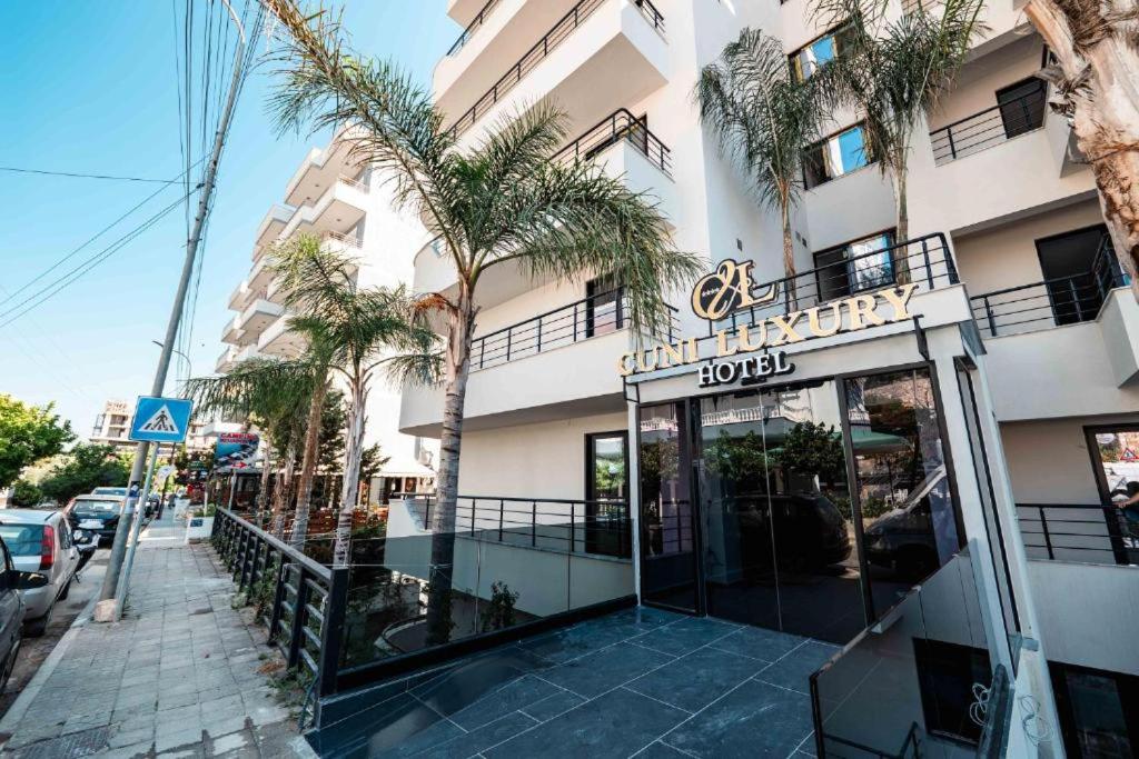 een hotel met palmbomen voor een gebouw bij Cuni Luxury Hotel in Sarandë