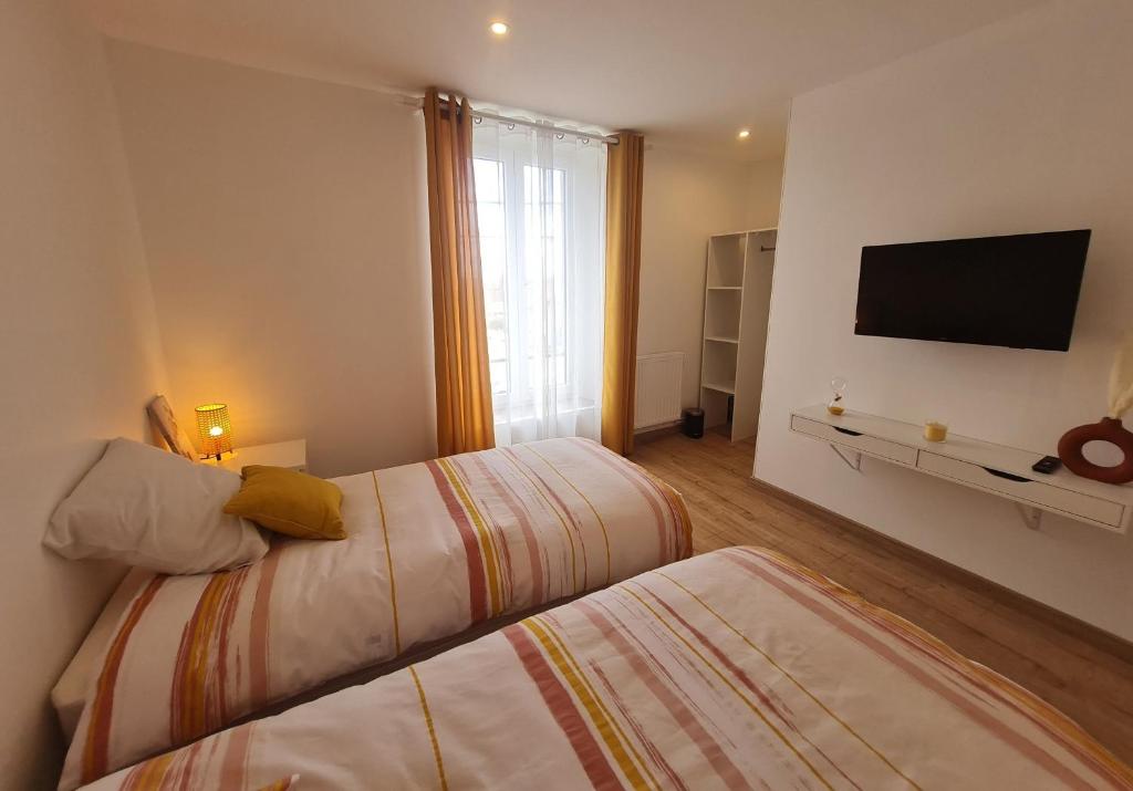 ein Schlafzimmer mit zwei Betten und einem Flachbildfernseher in der Unterkunft O p'tit nid à bulles in Létricourt