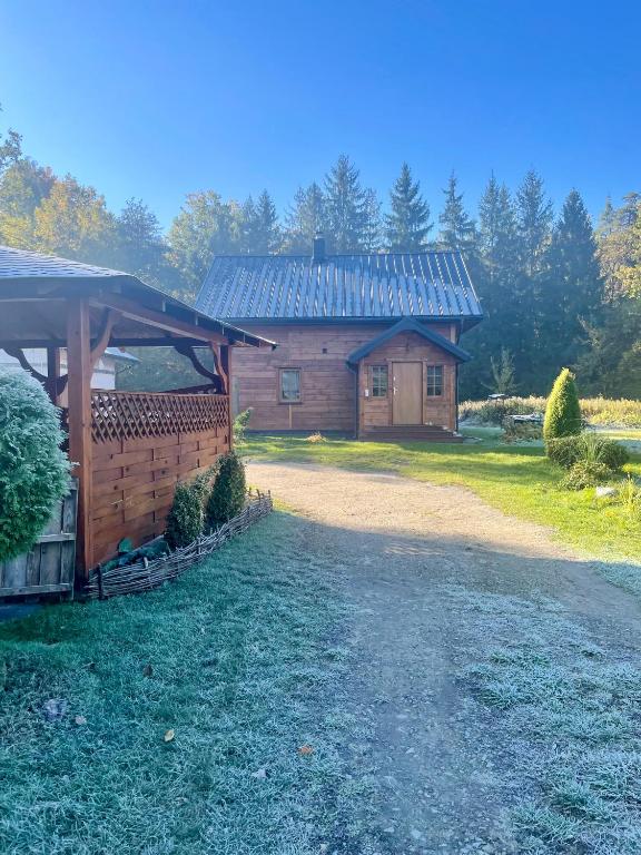 a wooden building with a tin roof on a yard at Gajówka Wiry in Pawłowa