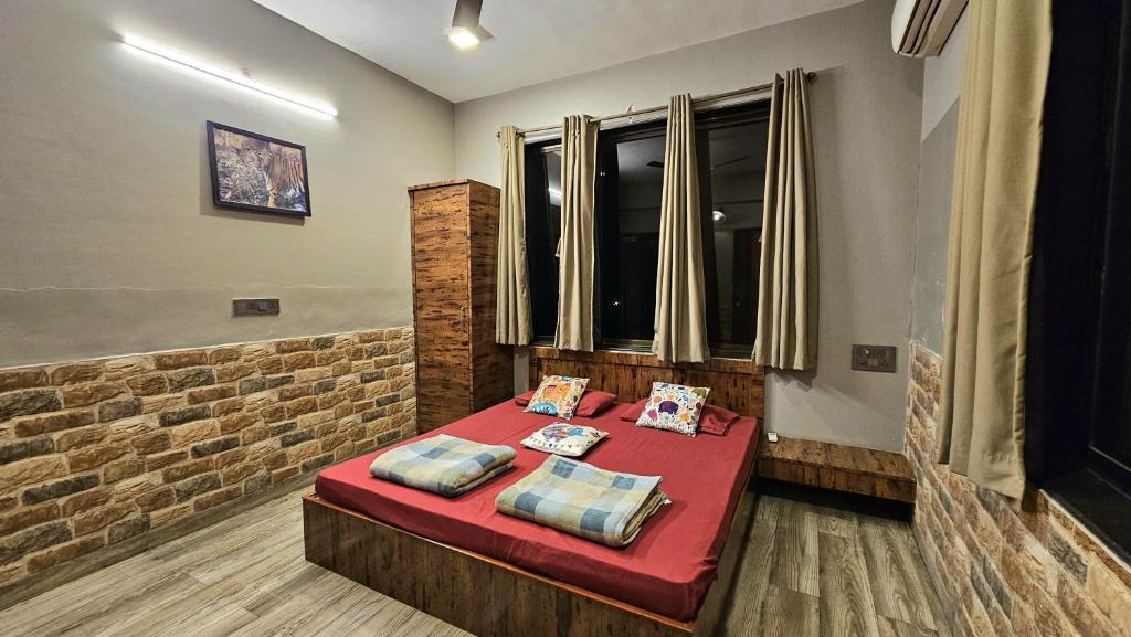 Cette chambre comprend un lit rouge avec des oreillers. dans l'établissement Elephant House Luxury Villa with Curve Pool-Colossal Garden-Panoramic View, à Lonavala