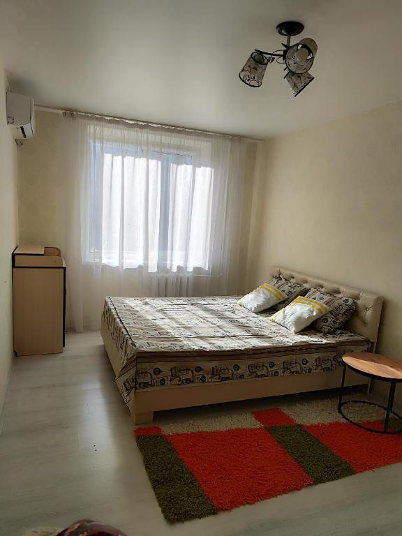 een slaapkamer met een bed met een raam en een tapijt bij Квартира в центре города Тирасполь in Crăsnăşeni