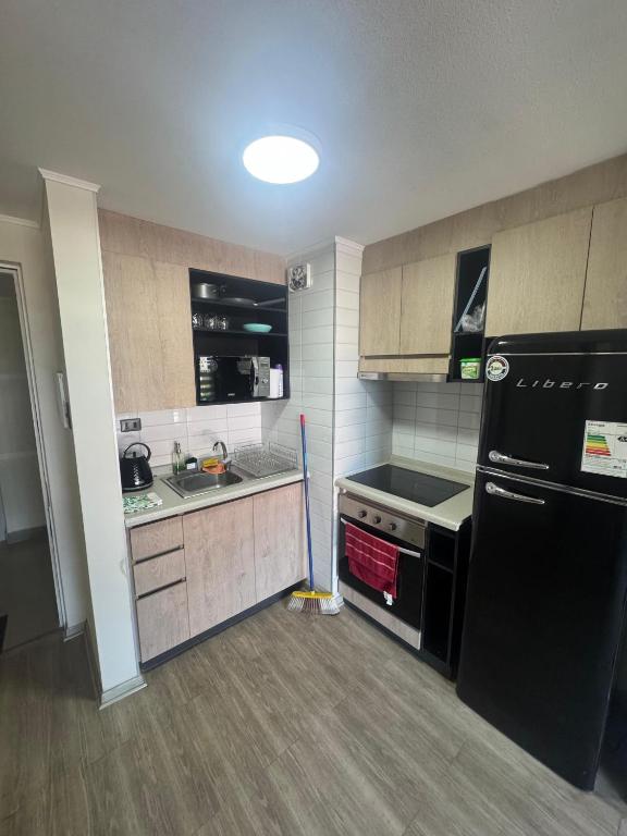 een keuken met een zwarte koelkast en een spoelbak bij Estacionamiento, Céntrico y Cómodo in Chillán