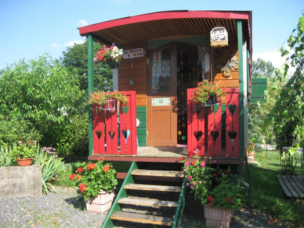a small house with red doors and flowers in front at La Roulotte d'Arthur in Sercoeur