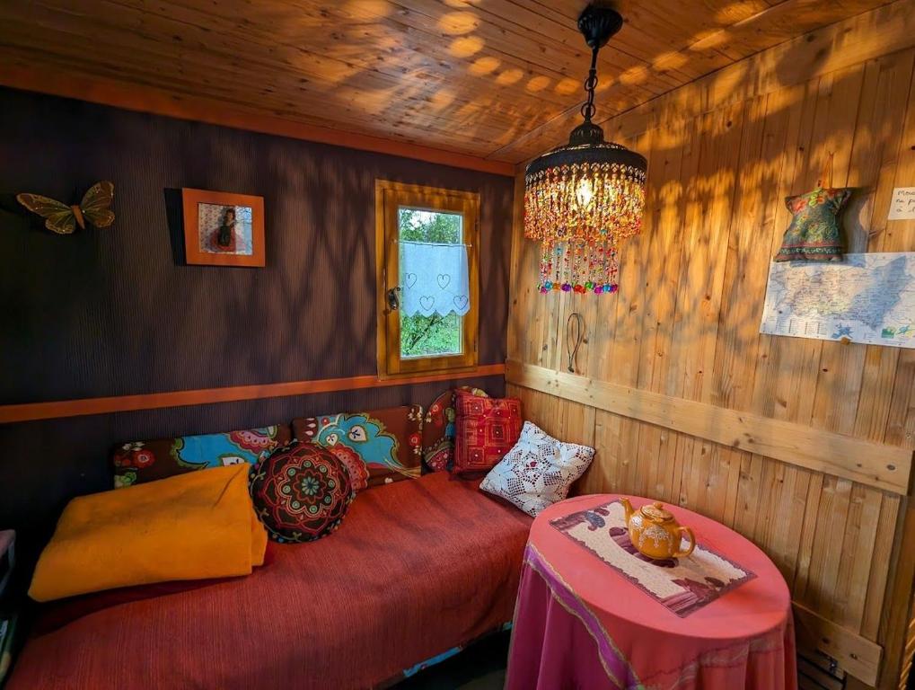 een slaapkamer met een rood bed en een kroonluchter bij La Roulotte d'Arthur in Sercoeur