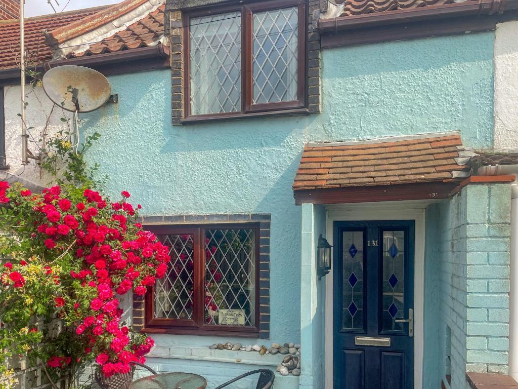 una casa blu con una porta blu e fiori di Turning Tides Cottage a Scratby
