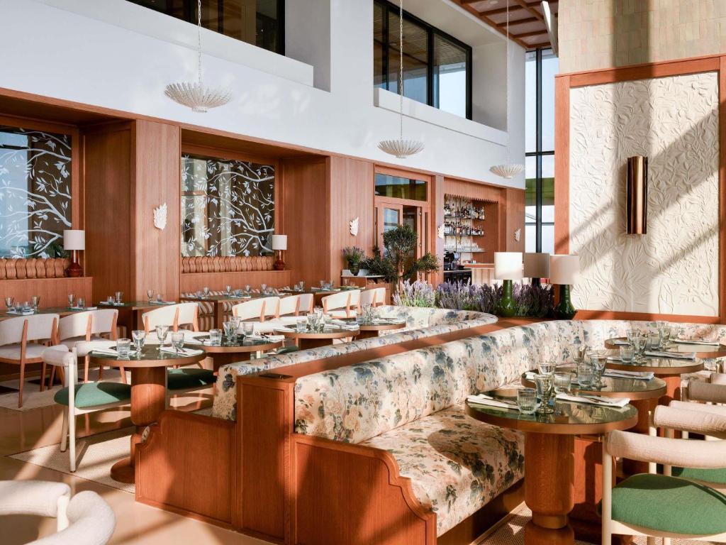 a restaurant with a long bench with tables and chairs at Novotel Abidjan Marcory in Abidjan