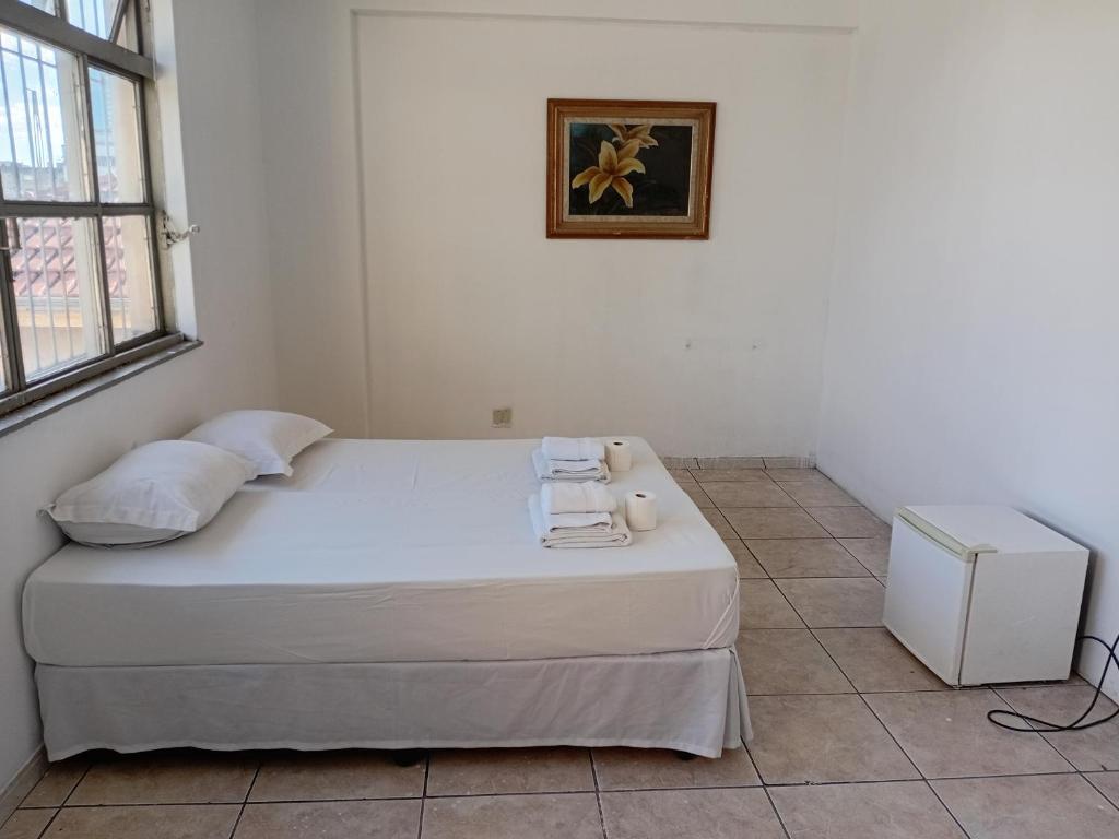 a bedroom with a white bed with towels on it at Hotel BH Center in Belo Horizonte