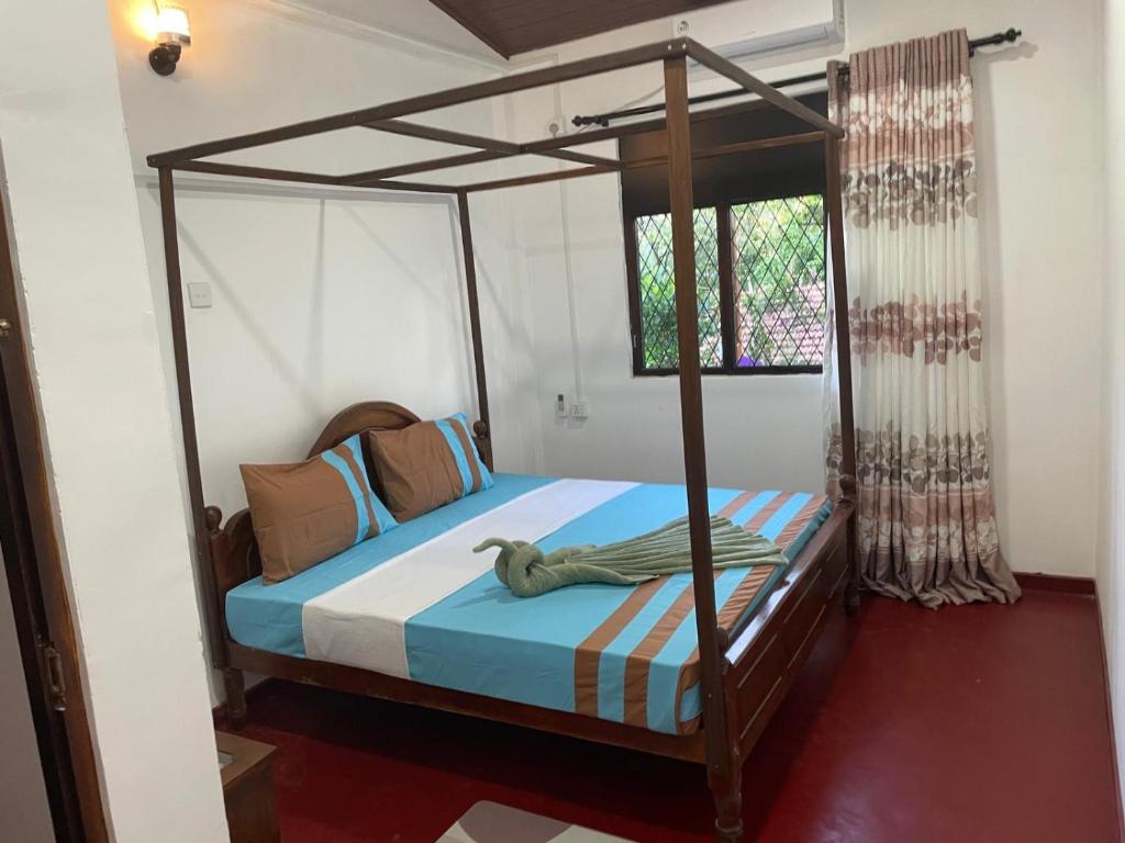 une chambre avec un lit à baldaquin dans une pièce dans l'établissement Femingo by Costels, à Hiriketiya