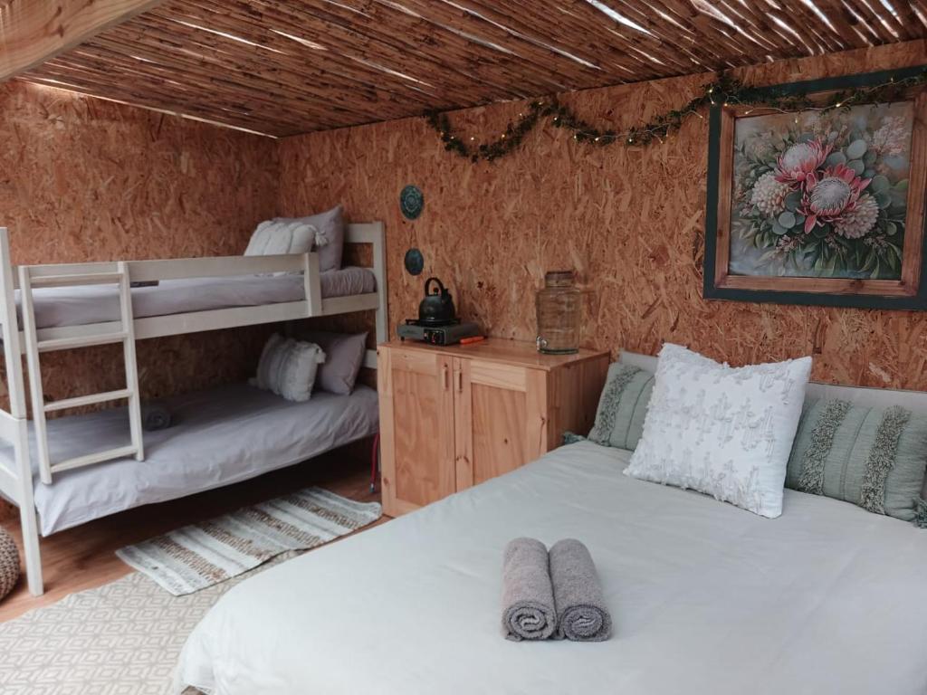 een slaapkamer met 2 bedden en een stapelbed bij Gaia River Cabin in Swellendam