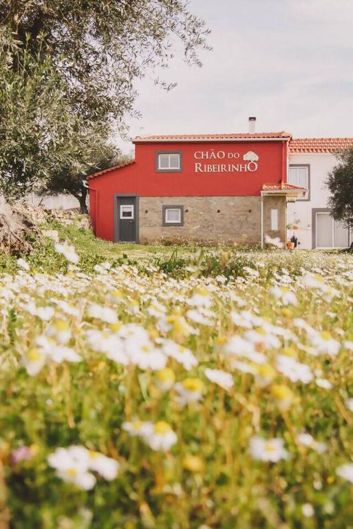 a red building with a sign on the side of it at Chão do Ribeirinho Country House in Atalaia