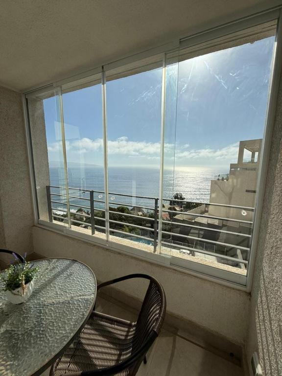 a table and chair in a balcony with a view of the ocean at Beautiful loft with ocean views in Reñaca in Viña del Mar