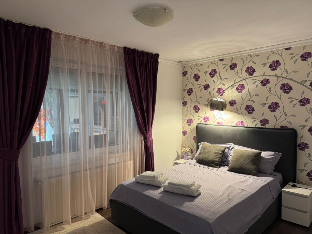 een slaapkamer met een bed met een bloemenmuur bij Casa Rosa by MANAGR in Piatra Neamţ