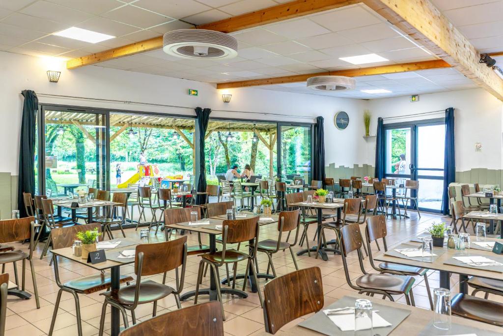 une salle à manger avec tables, chaises et fenêtres dans l'établissement Camping Capfun La Bretèche, aux Épesses