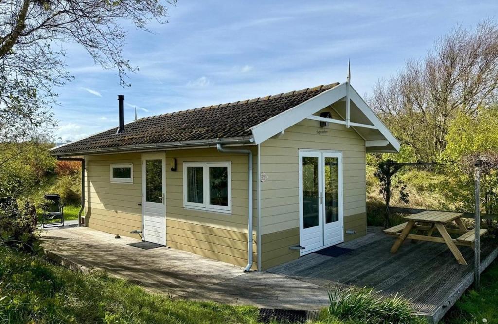 a small shed with a picnic table on a deck at DuinHut with Hottub in Ons Belang