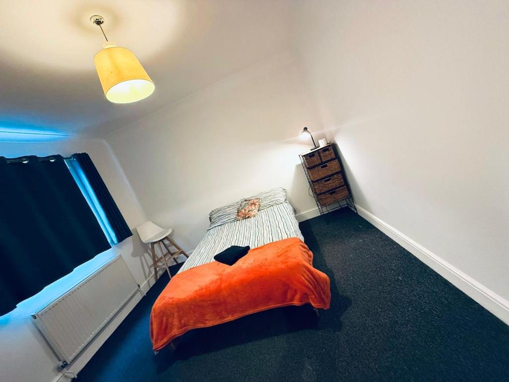 een slaapkamer met een bed met een oranje deken bij Pebbles Guest House - Flat 5 in Southampton