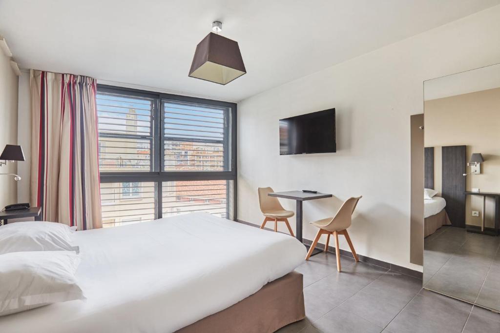a bedroom with a bed and a table and a window at Appart'hôtel Odalys City - Marseille Centre Parc Chanot Vélodrome in Marseille