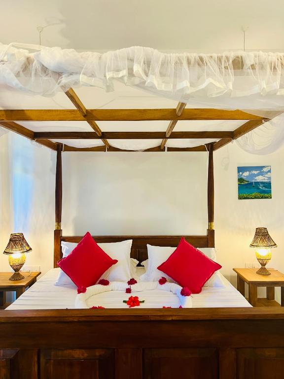 a bedroom with a bed with red and white pillows at Sunburst Villa in Tangalle