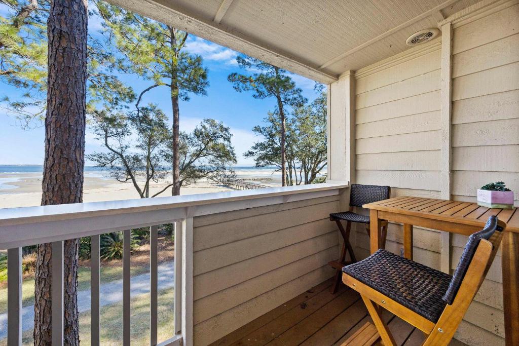 een tafel en stoel op een veranda met uitzicht op het strand bij Oceanfront Sunrises on Mitchelville Beach in Hilton Head Island