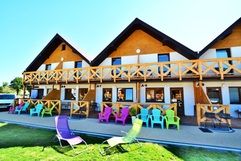 a house with colorful chairs and tables in front of it at Tropikana Domki, Apartamenty in Mielno