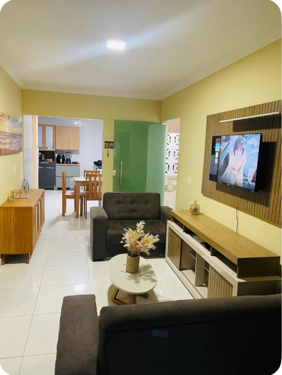 a living room with a couch and a tv on a wall at Casa Maragogi in Maragogi